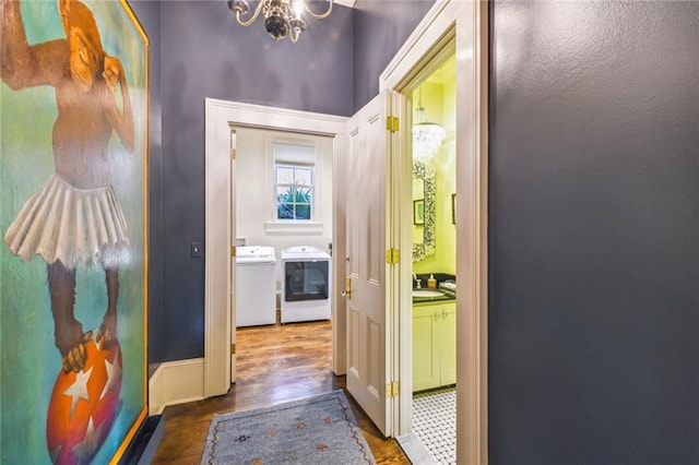 corridor featuring a chandelier, dark hardwood / wood-style flooring, washing machine and dryer, and sink