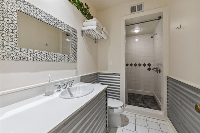 bathroom with tiled shower, vanity, and toilet