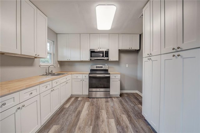 kitchen featuring white cabinetry, stainless steel appliances, sink, and light hardwood / wood-style flooring