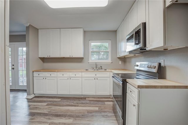 kitchen with white cabinetry, stainless steel appliances, light hardwood / wood-style floors, and sink