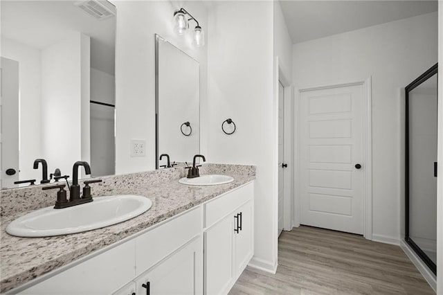 bathroom with wood-type flooring, vanity, and a shower with shower door