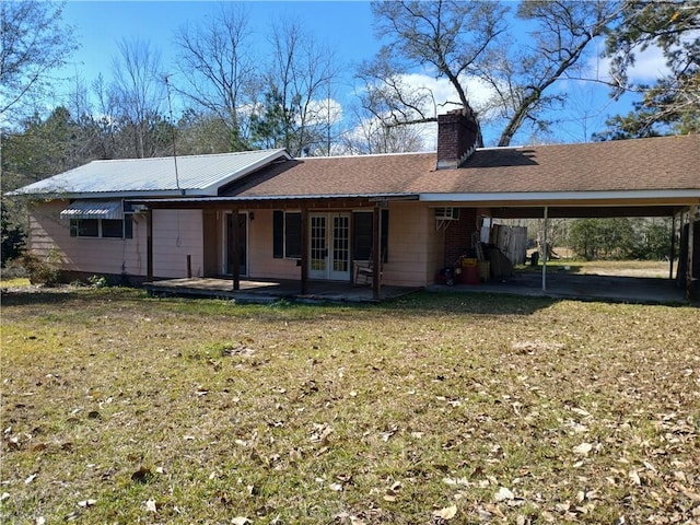 rear view of property with french doors, a carport, and a lawn