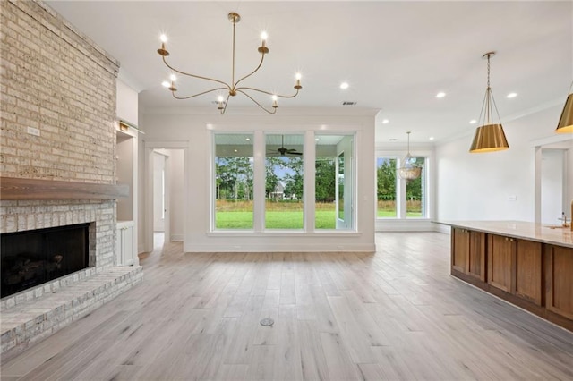 unfurnished living room with a fireplace, light hardwood / wood-style floors, a chandelier, and crown molding