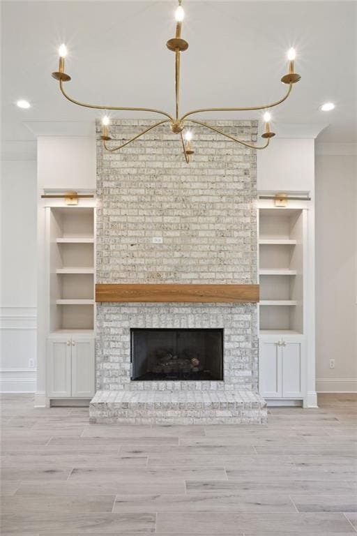 unfurnished living room with a brick fireplace, light hardwood / wood-style floors, ornamental molding, and built in shelves