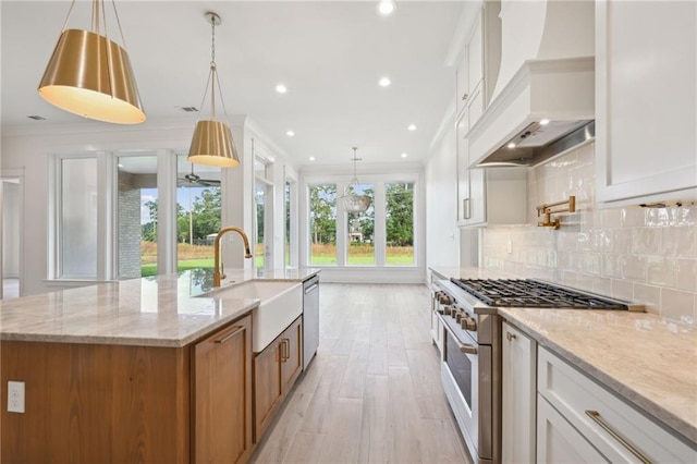 kitchen featuring stainless steel appliances, sink, custom exhaust hood, a kitchen island with sink, and white cabinetry