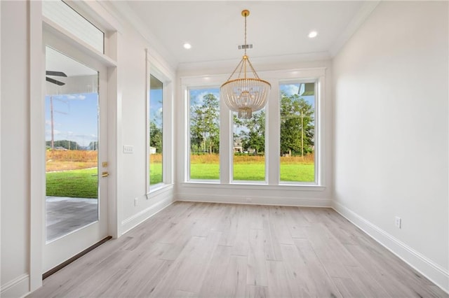 unfurnished sunroom featuring ceiling fan with notable chandelier and a wealth of natural light