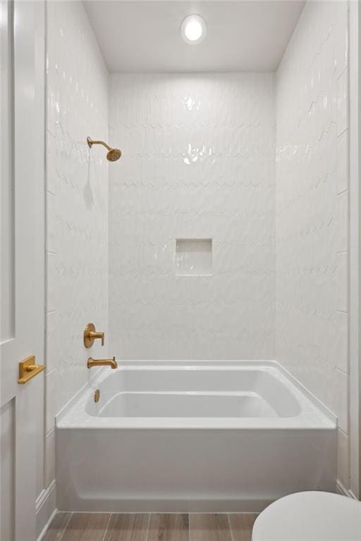 bathroom featuring tiled shower / bath and toilet