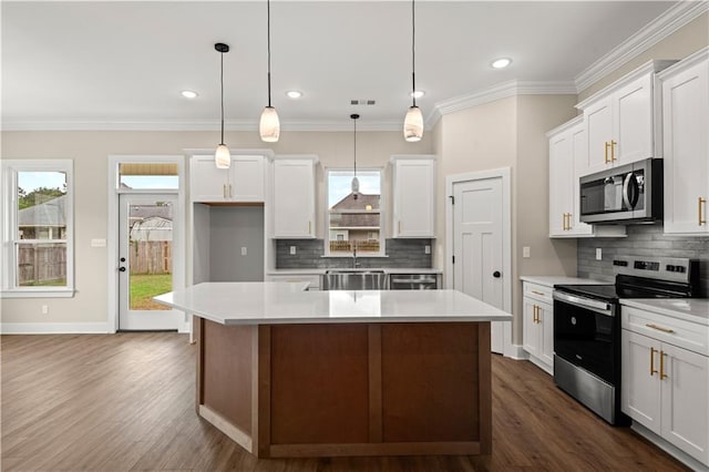 kitchen featuring a wealth of natural light, decorative light fixtures, appliances with stainless steel finishes, and a center island