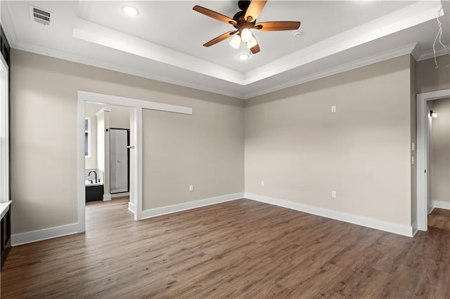 spare room featuring ornamental molding, wood-type flooring, and a raised ceiling