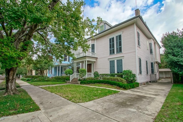 1521 Dufossat St, New Orleans, LA 70115 - view of front facade with a balcony, a front lawn, and a chimney