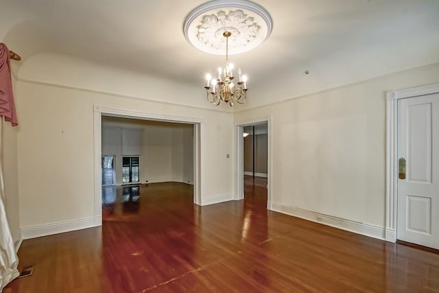 spare room with dark hardwood / wood-style flooring and a chandelier