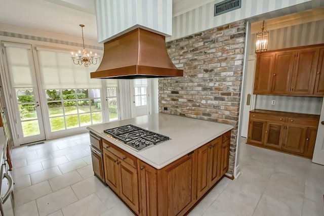 1521 Dufossat St, New Orleans, LA 70115 - kitchen featuring island range hood, a chandelier, wallpapered walls, stainless steel gas cooktop, and brown cabinetry
