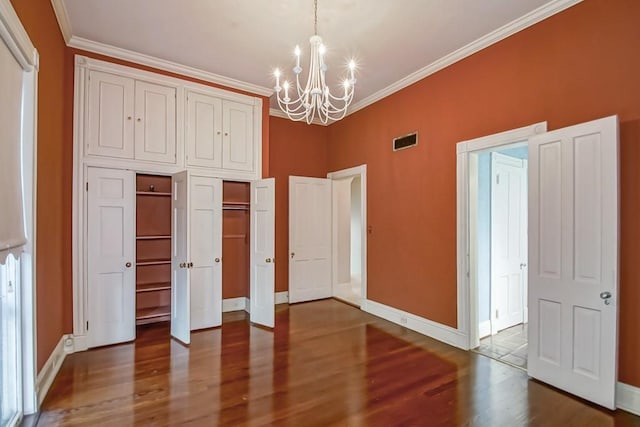 unfurnished bedroom featuring a chandelier, hardwood / wood-style flooring, crown molding, and a closet