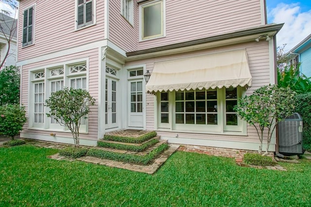 back of property featuring central AC and a lawn