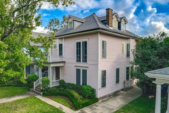 1521 Dufossat St, New Orleans, LA 70115 - view of home's exterior with a lawn, a balcony, a chimney, and roof with shingles