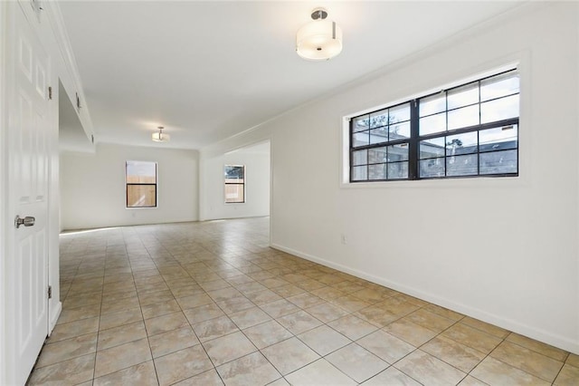 spare room featuring a wealth of natural light, light tile patterned floors, and ornamental molding