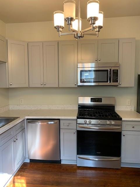 kitchen featuring hanging light fixtures, white cabinets, dark wood-type flooring, and appliances with stainless steel finishes