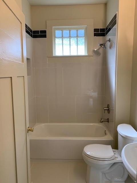 full bathroom with tiled shower / bath, tile patterned floors, toilet, and sink