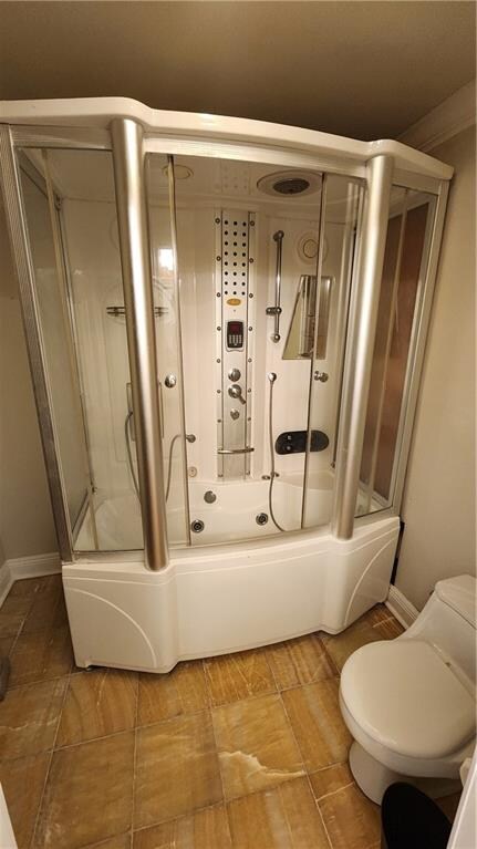 bathroom with combined bath / shower with glass door and toilet