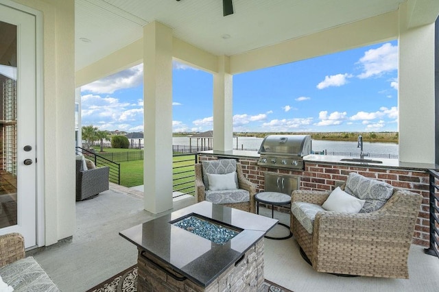 view of patio with grilling area, sink, a water view, exterior kitchen, and a fire pit