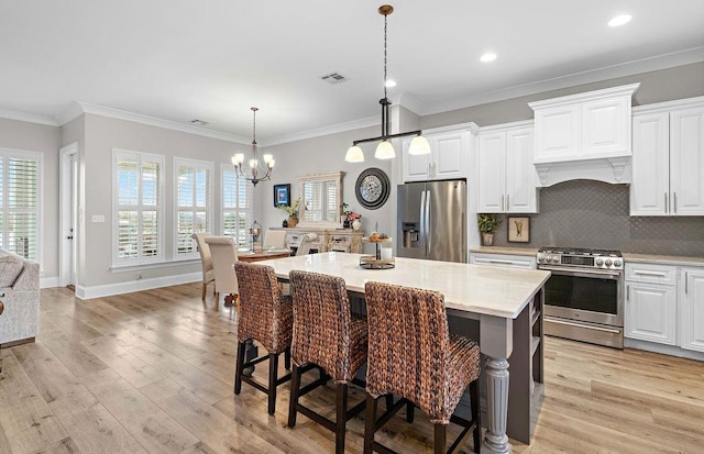 kitchen featuring stainless steel appliances, white cabinets, a kitchen island with sink, and light hardwood / wood-style flooring