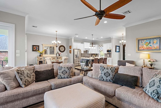 living room with ceiling fan with notable chandelier, hardwood / wood-style flooring, and crown molding