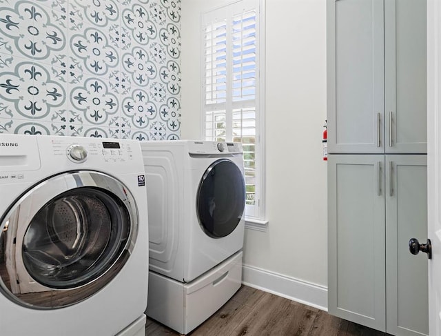 laundry area with washing machine and dryer, a wealth of natural light, and cabinets