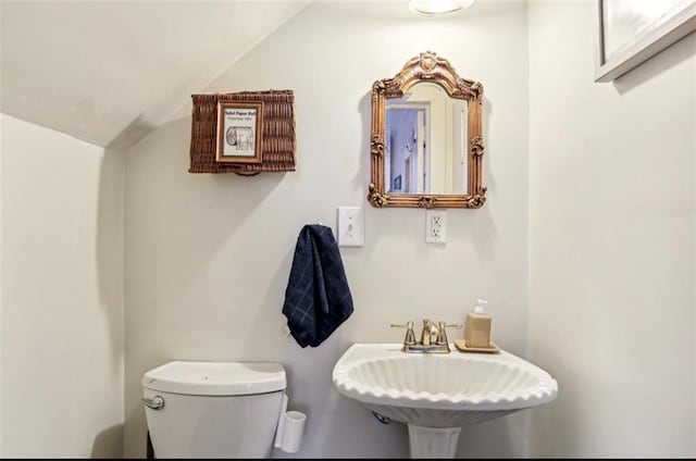 bathroom featuring toilet, sink, and vaulted ceiling