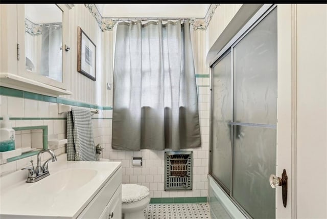 full bathroom with enclosed tub / shower combo, heating unit, vanity, toilet, and tile walls