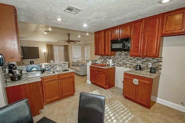 kitchen with light stone countertops, ceiling fan, a textured ceiling, and tasteful backsplash