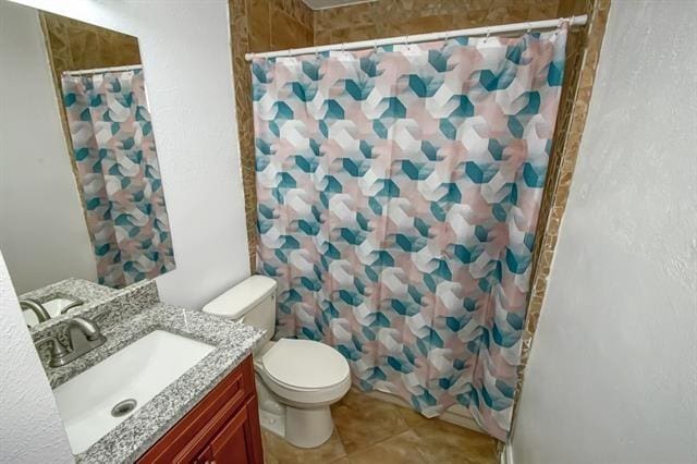 bathroom featuring toilet, vanity, tile patterned floors, and a shower with curtain