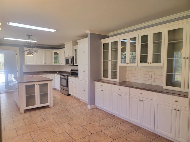 kitchen with glass insert cabinets, ornamental molding, white cabinets, and appliances with stainless steel finishes