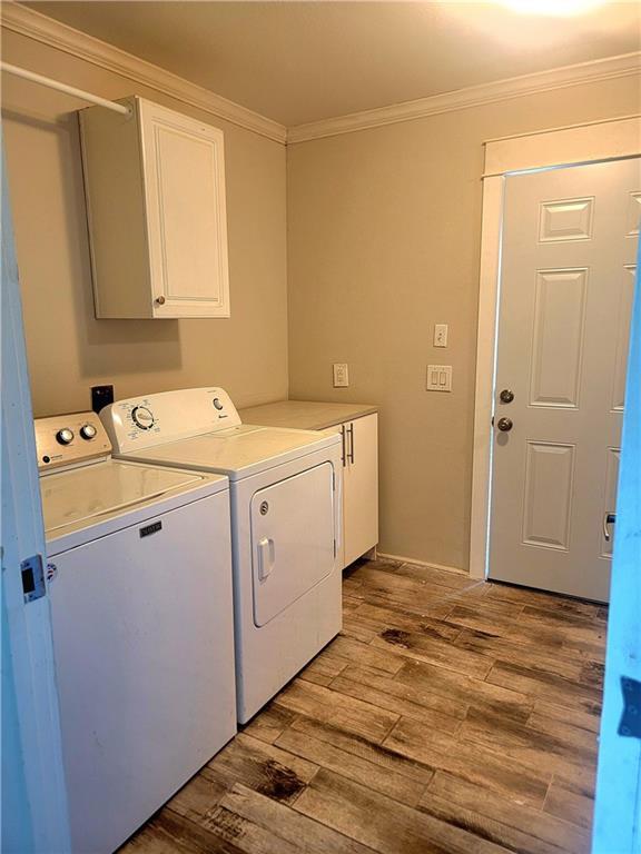 clothes washing area with separate washer and dryer, ornamental molding, cabinet space, and light wood-type flooring