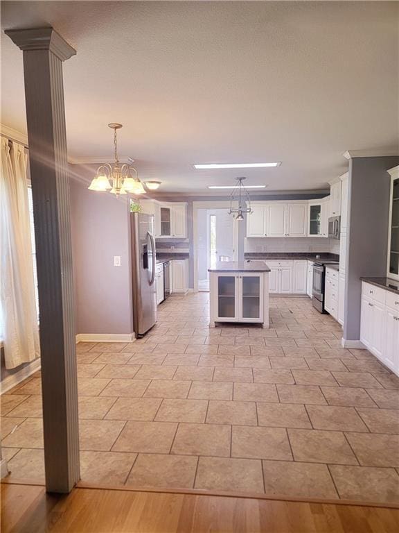 kitchen with white cabinets, glass insert cabinets, stainless steel appliances, decorative light fixtures, and an inviting chandelier