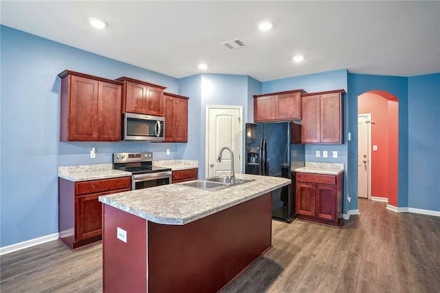 kitchen with dark hardwood / wood-style flooring, sink, an island with sink, and stainless steel appliances