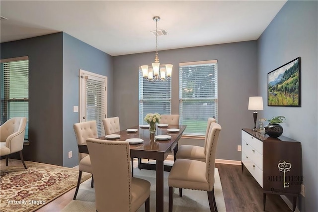 dining space with dark hardwood / wood-style floors and a chandelier