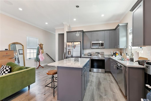 kitchen featuring appliances with stainless steel finishes, hanging light fixtures, light hardwood / wood-style flooring, a center island, and gray cabinets