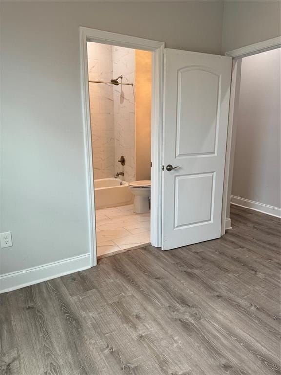 unfurnished bedroom featuring hardwood / wood-style floors and ensuite bath