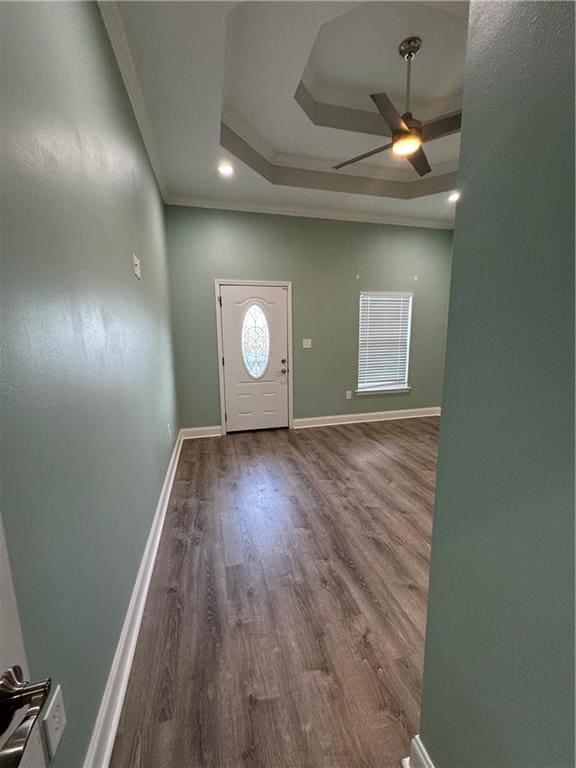 foyer entrance with ceiling fan, a tray ceiling, hardwood / wood-style flooring, and ornamental molding