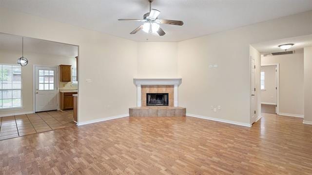 unfurnished living room featuring a fireplace, ceiling fan, and light wood-type flooring