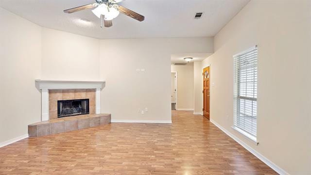 unfurnished living room with light wood-type flooring, ceiling fan, and a fireplace