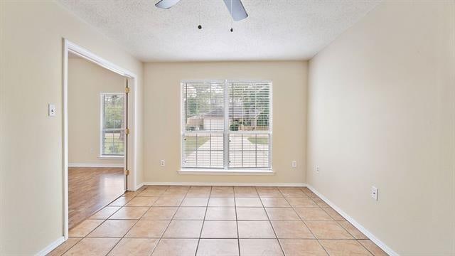 spare room with a textured ceiling, ceiling fan, and light tile patterned flooring