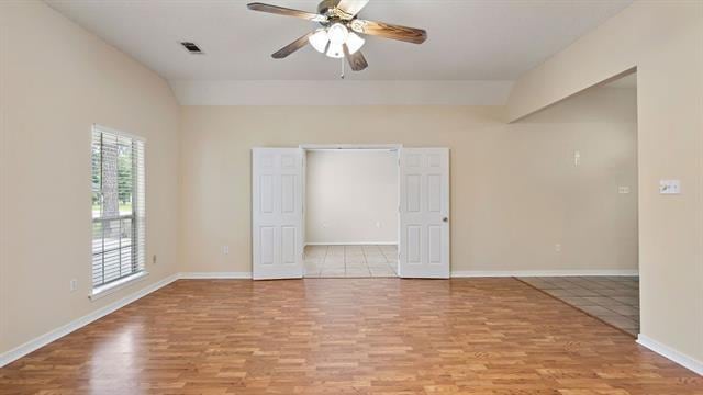 empty room with ceiling fan, light hardwood / wood-style flooring, and vaulted ceiling