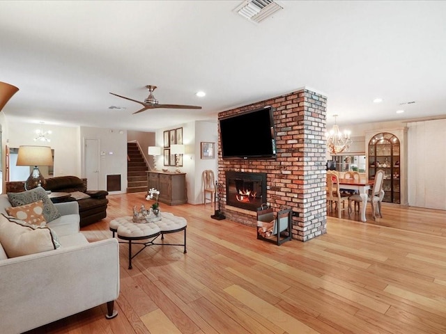 living room with a brick fireplace, ceiling fan, and light wood-type flooring