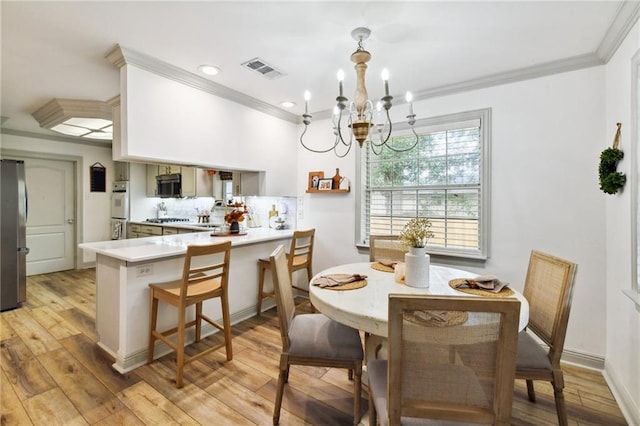 dining space with light wood-type flooring, crown molding, and a notable chandelier