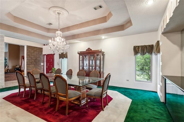 dining room with a chandelier, dark colored carpet, and a tray ceiling