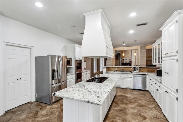 kitchen featuring light stone counters, stainless steel appliances, a kitchen island, white cabinetry, and hanging light fixtures