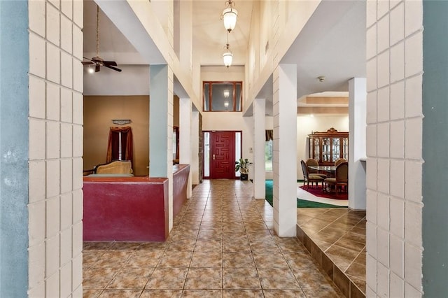 entrance foyer featuring tile patterned floors, ceiling fan, and a high ceiling