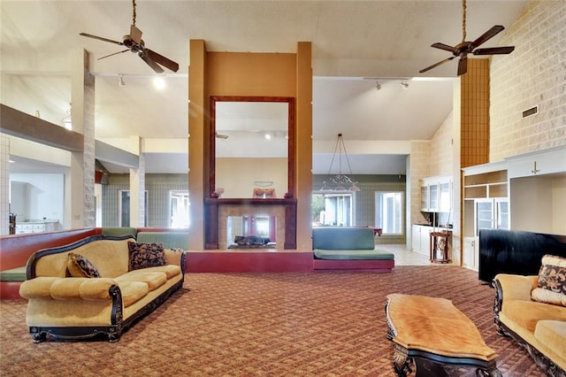 living room featuring a high ceiling, rail lighting, and a large fireplace