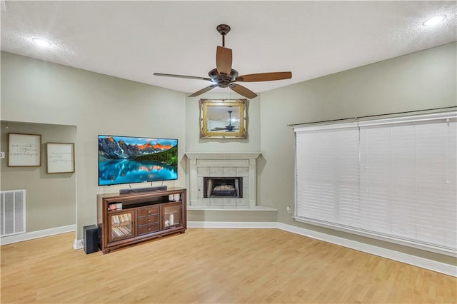 unfurnished living room featuring ceiling fan, hardwood / wood-style flooring, and a tiled fireplace